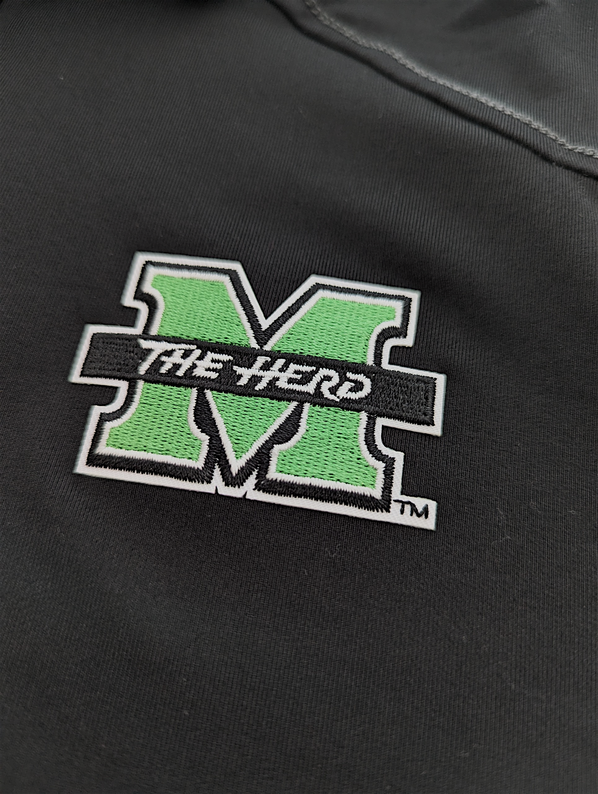 Black polo with green and white marshall logo on a dark background