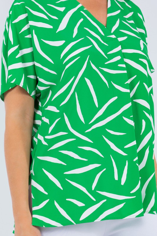 The green and white palm print top is shown in a frontal view in a close up with printed detail