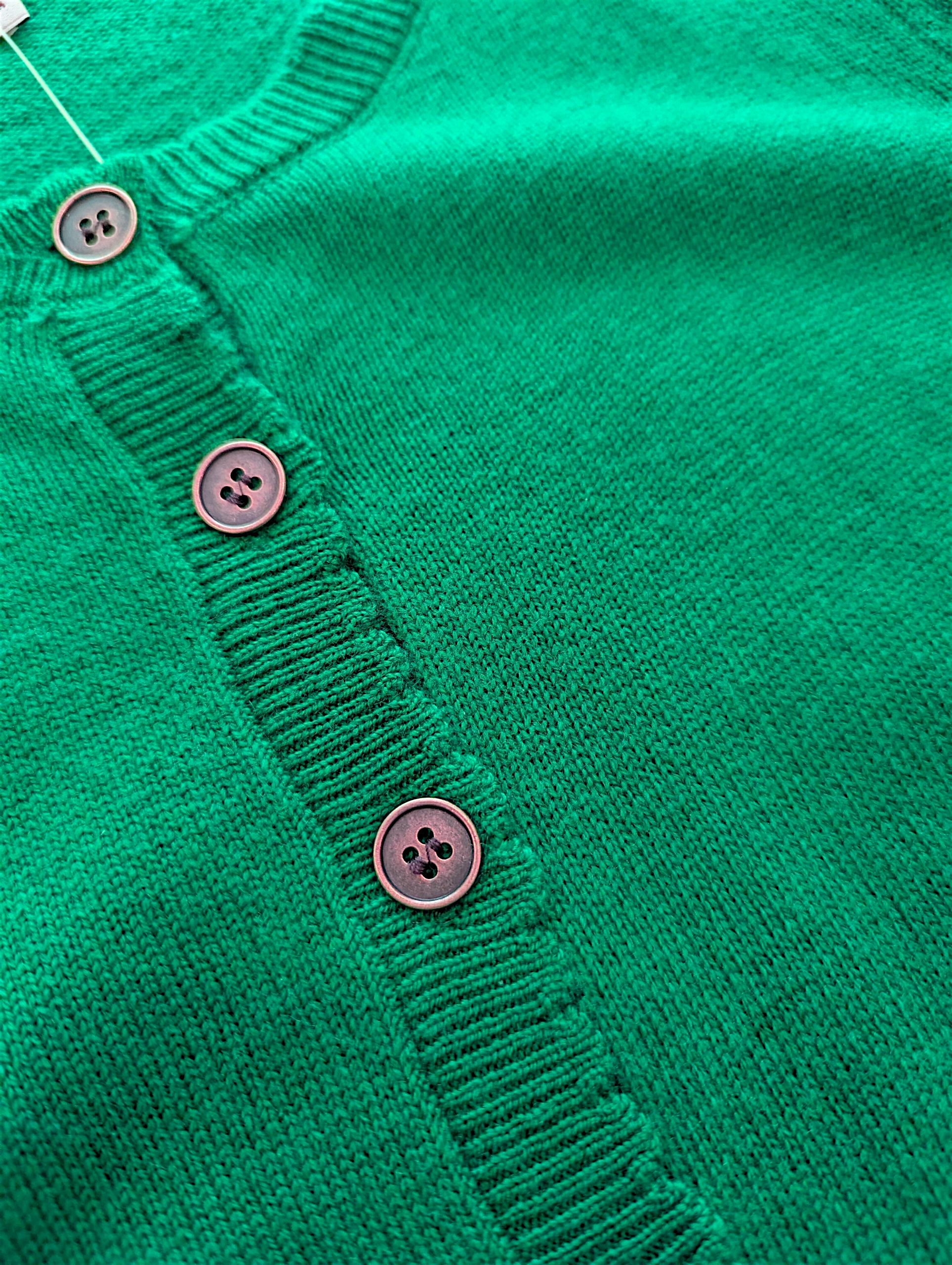 Close-up of a green cardigan with buttons on a white background