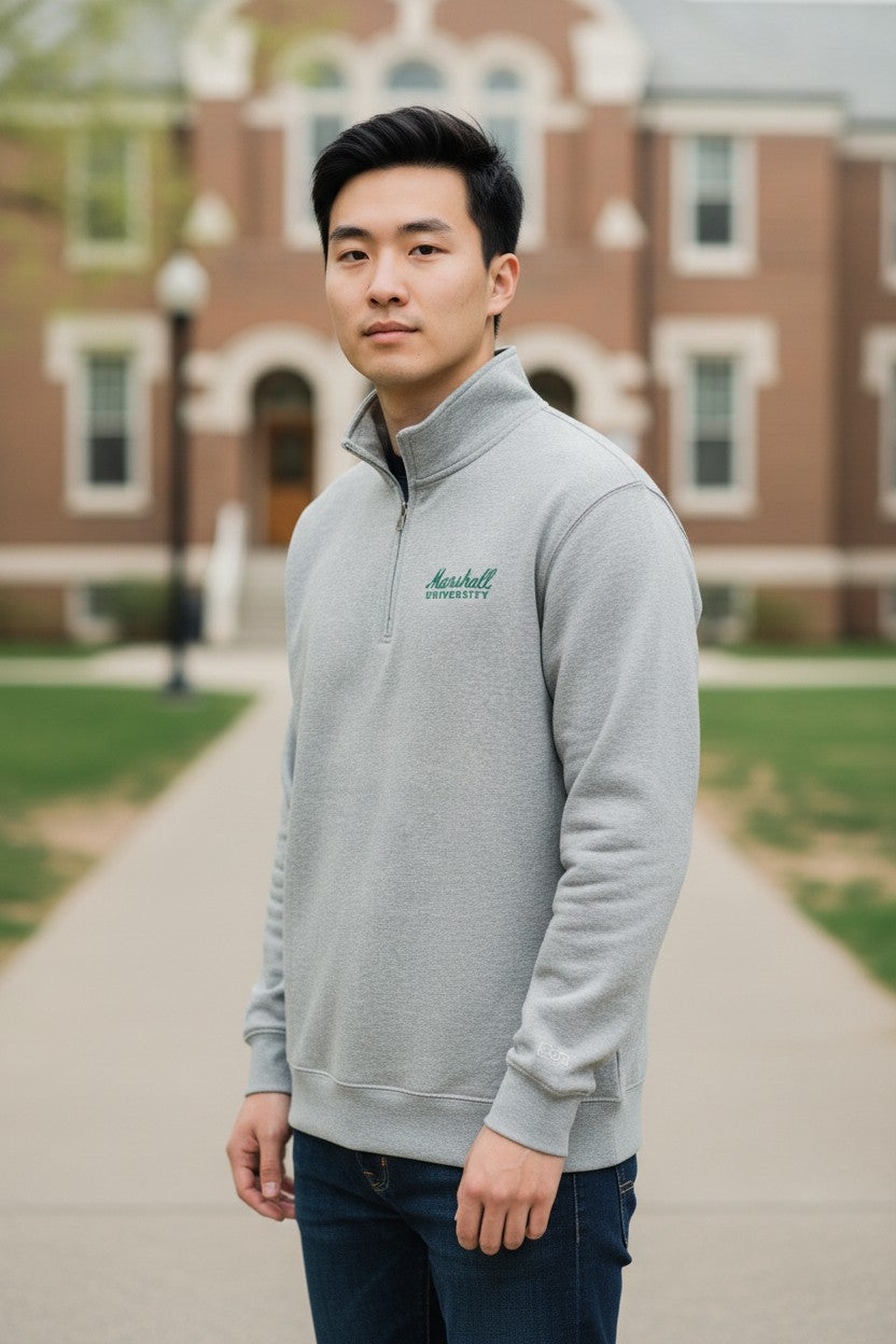 Man wearing a gray sweater with a logo in front of a brick building