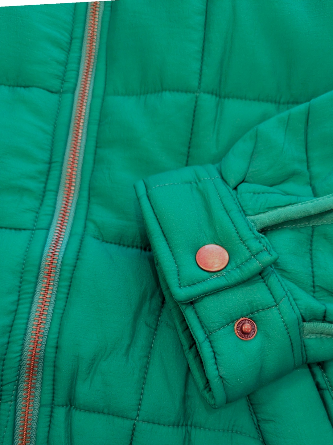 Close-up of a green quilted jacket with buttons and zipper