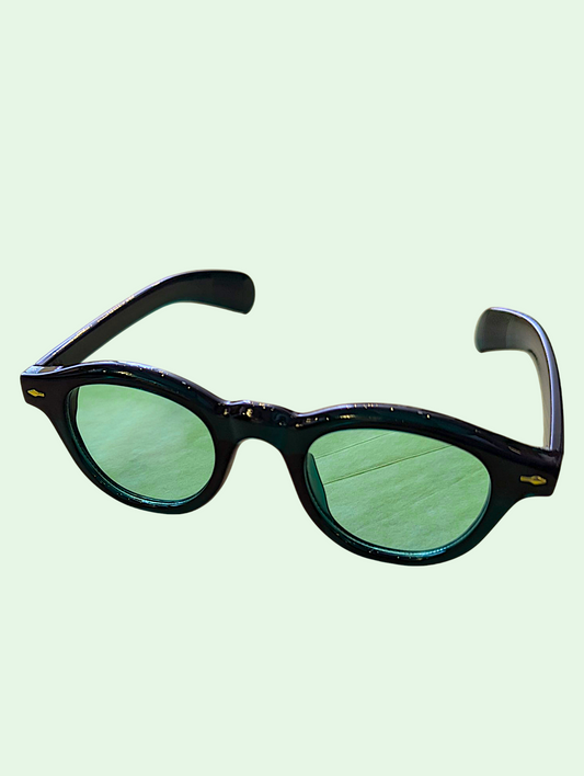 Sunglasses with green lenses and black frame on a light green background