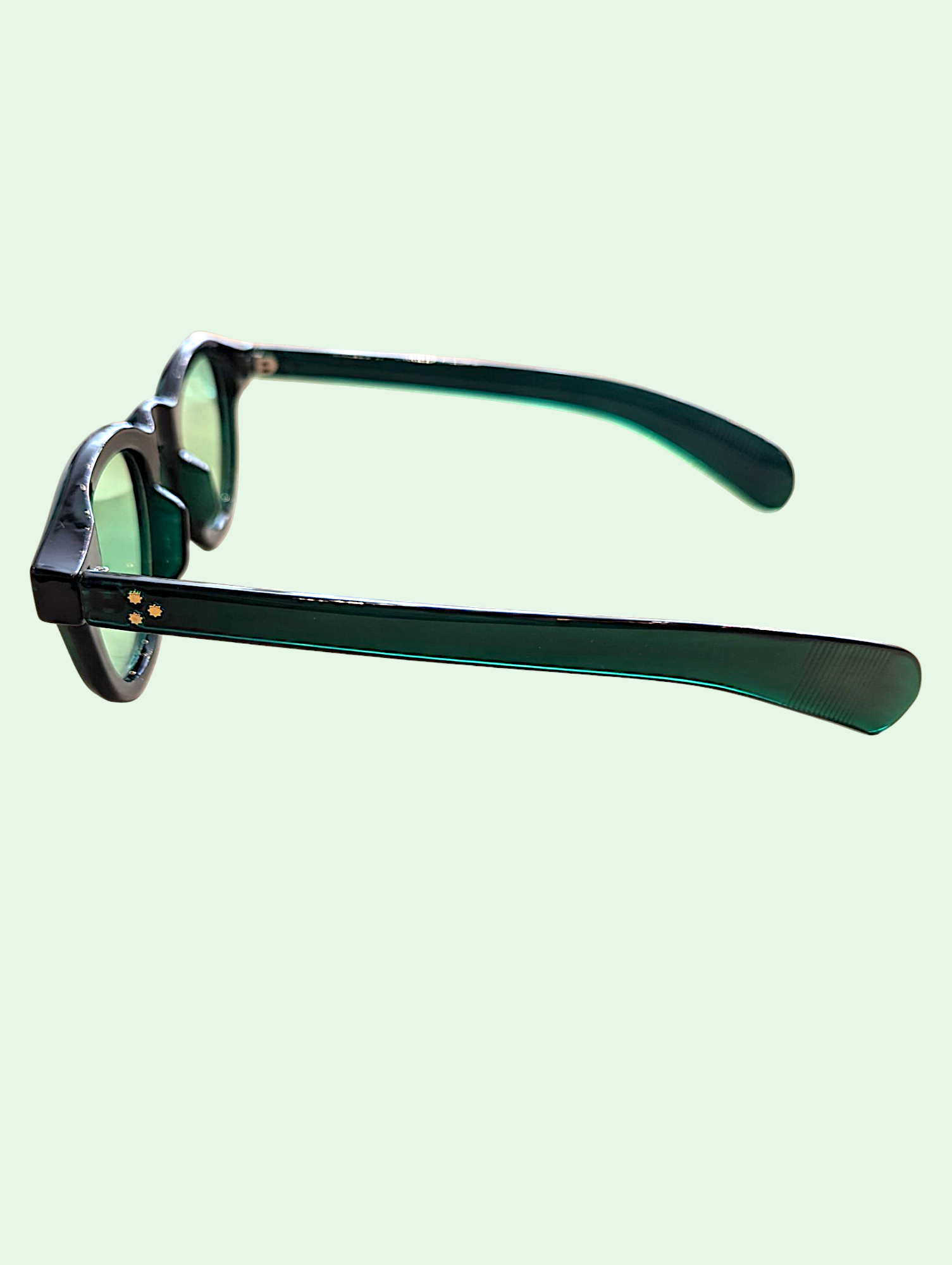 Sunglasses with green-tinted lenses on a light green background