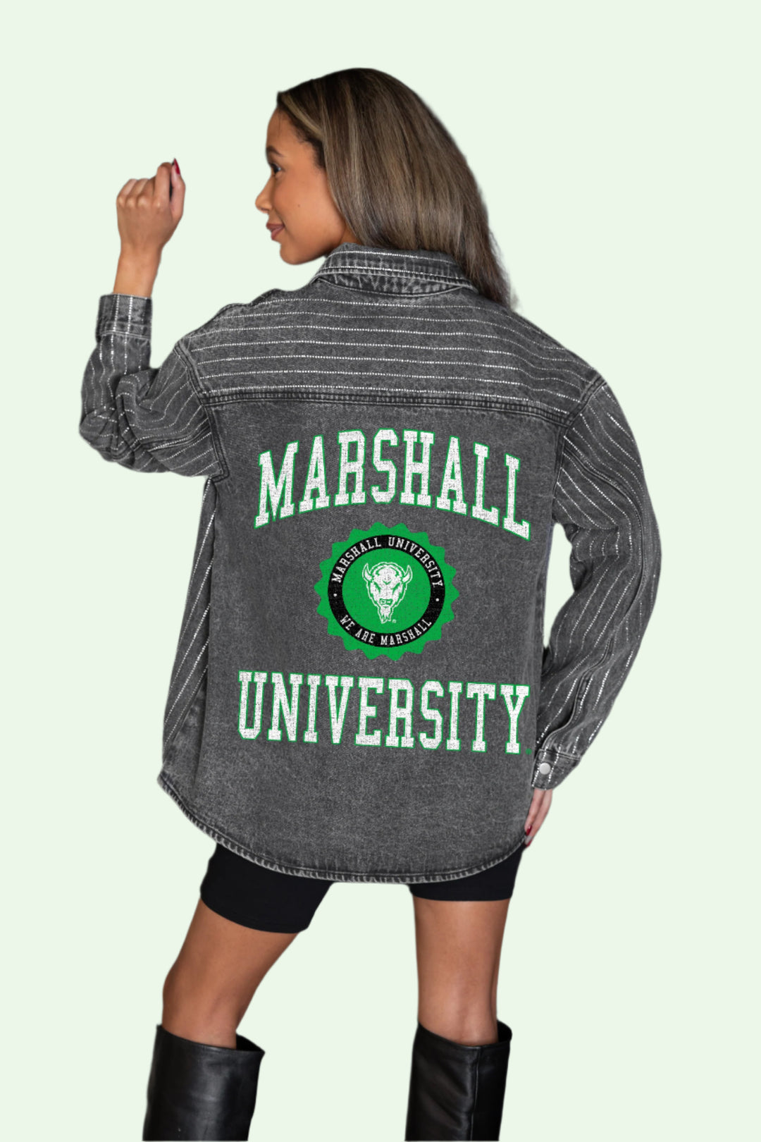 Person wearing a gray 'Marshall University' jacket with a logo, standing against a dark background.