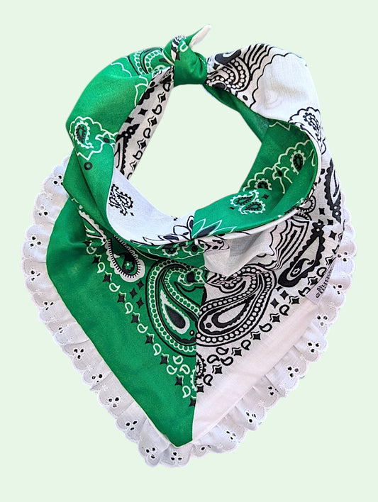 A green and white bandana-style neck gaiter with black paisley patterns and white ruffled trim, shown on a pale mint green background.