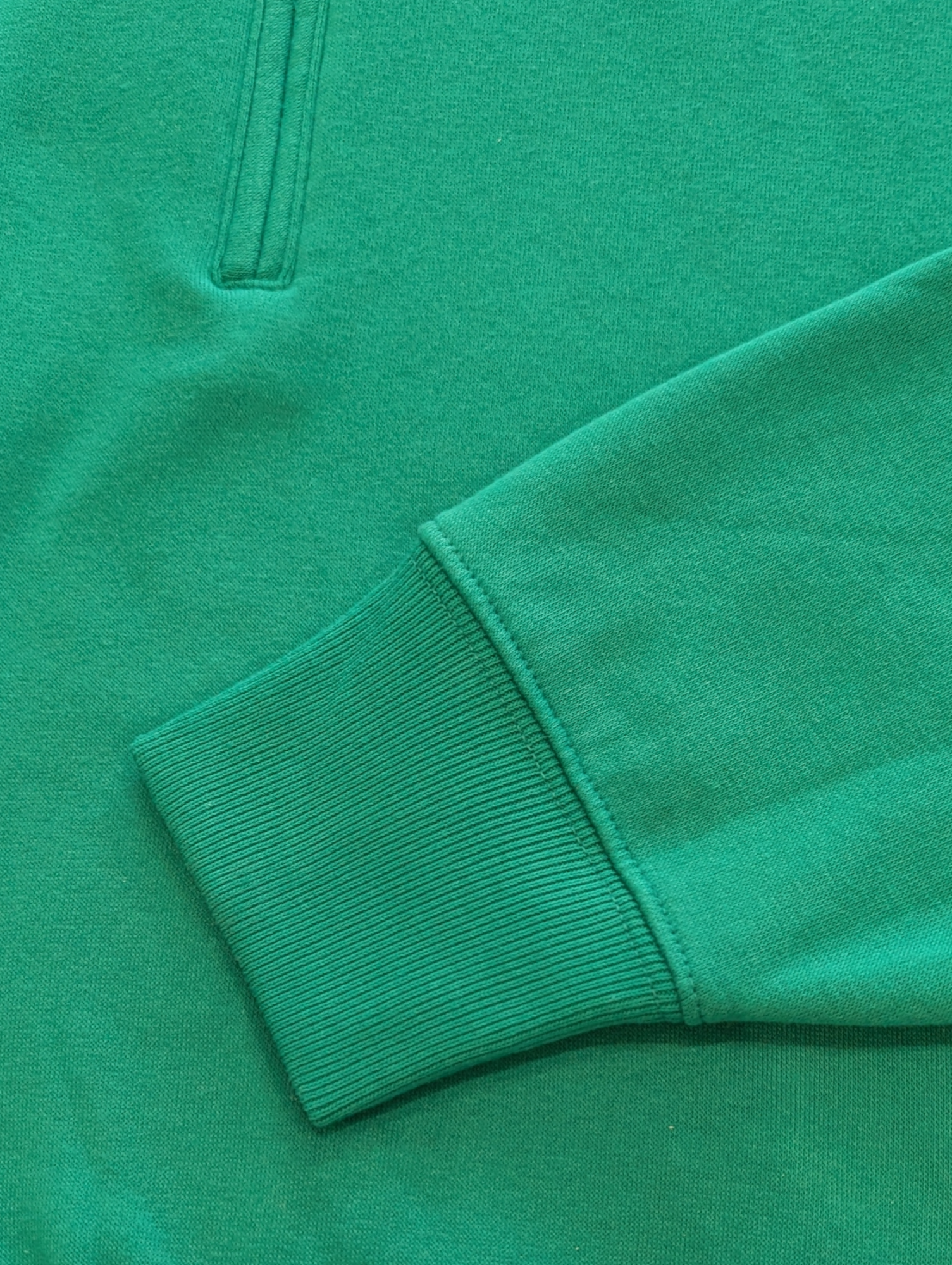 Close-up of a green sweatshirt with a focus on the sleeve and collar.