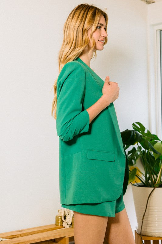 a model stands sideways in a kelly green blazer