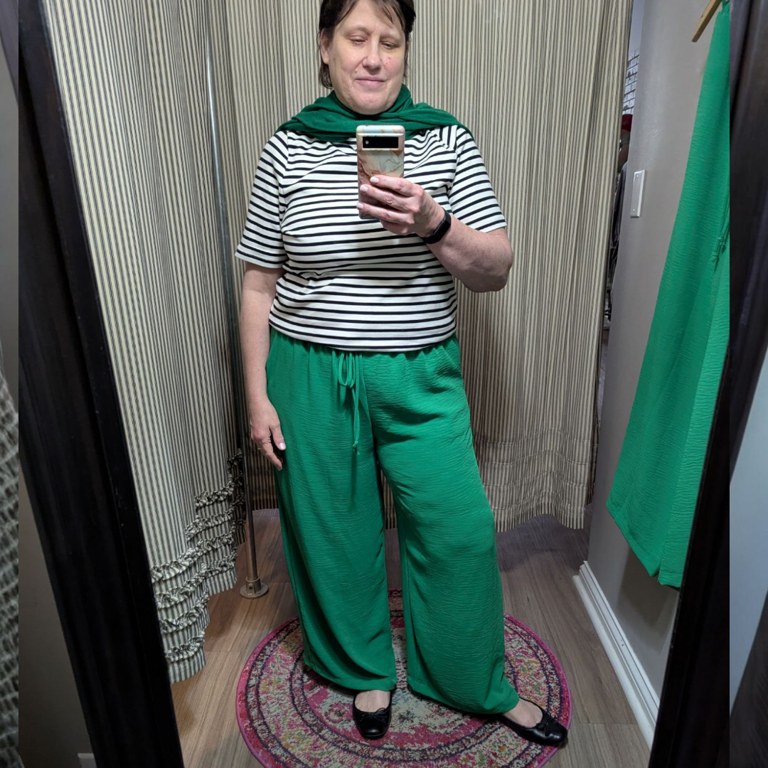 a shot of sara in the airflow pants, with a striped tee and green sweater around her shoulders