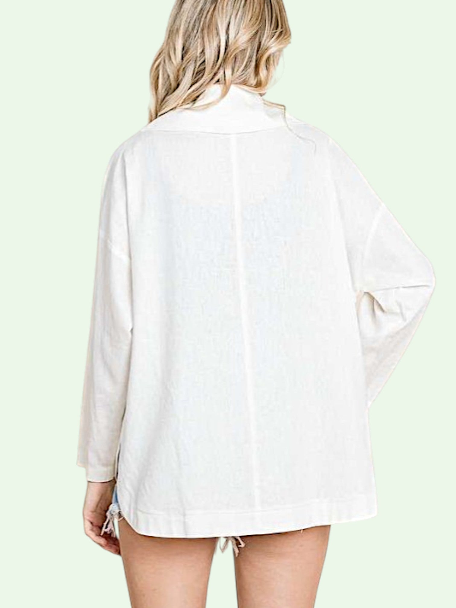 Person wearing a white jacket with long sleeves on a light green background