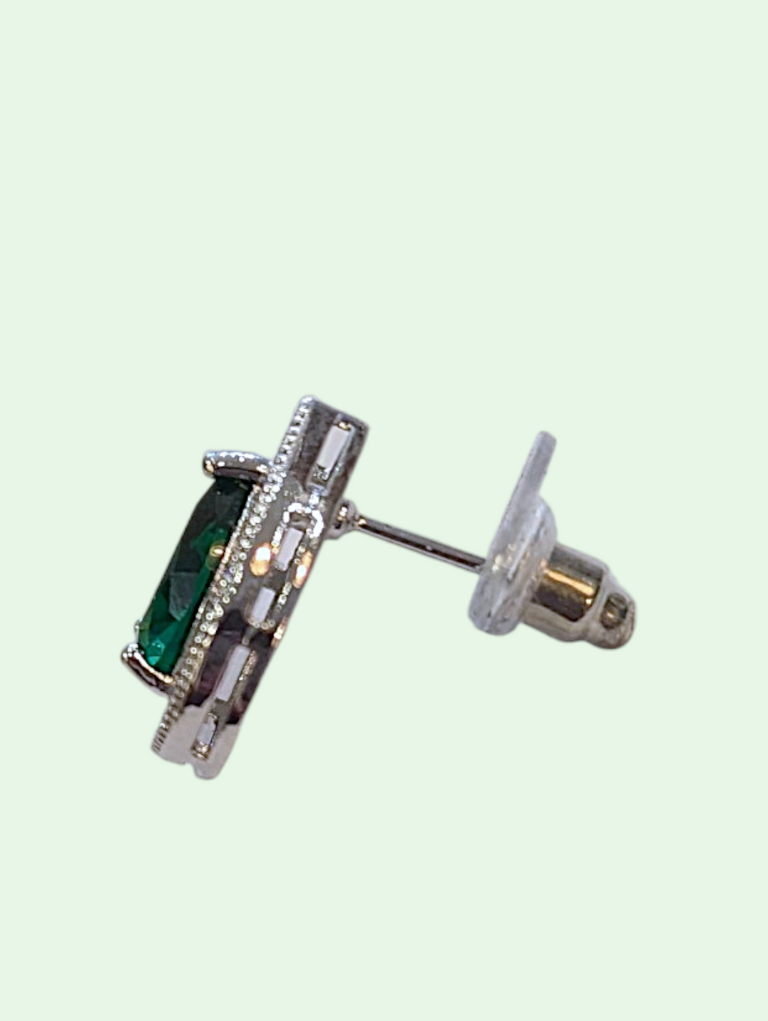 Silver earring with green gemstone on a light green background