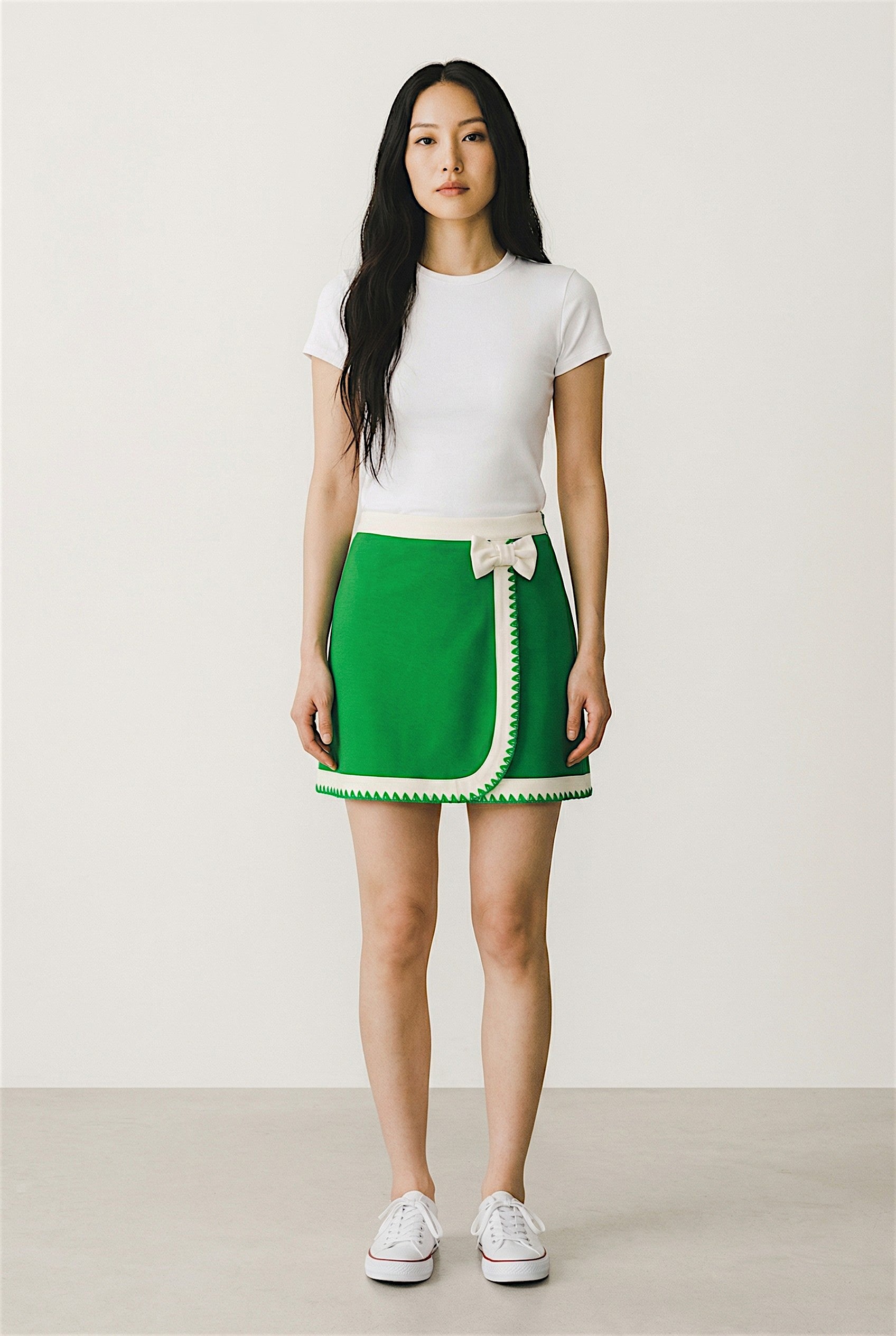 Woman wearing a white t-shirt and green skirt with a white background