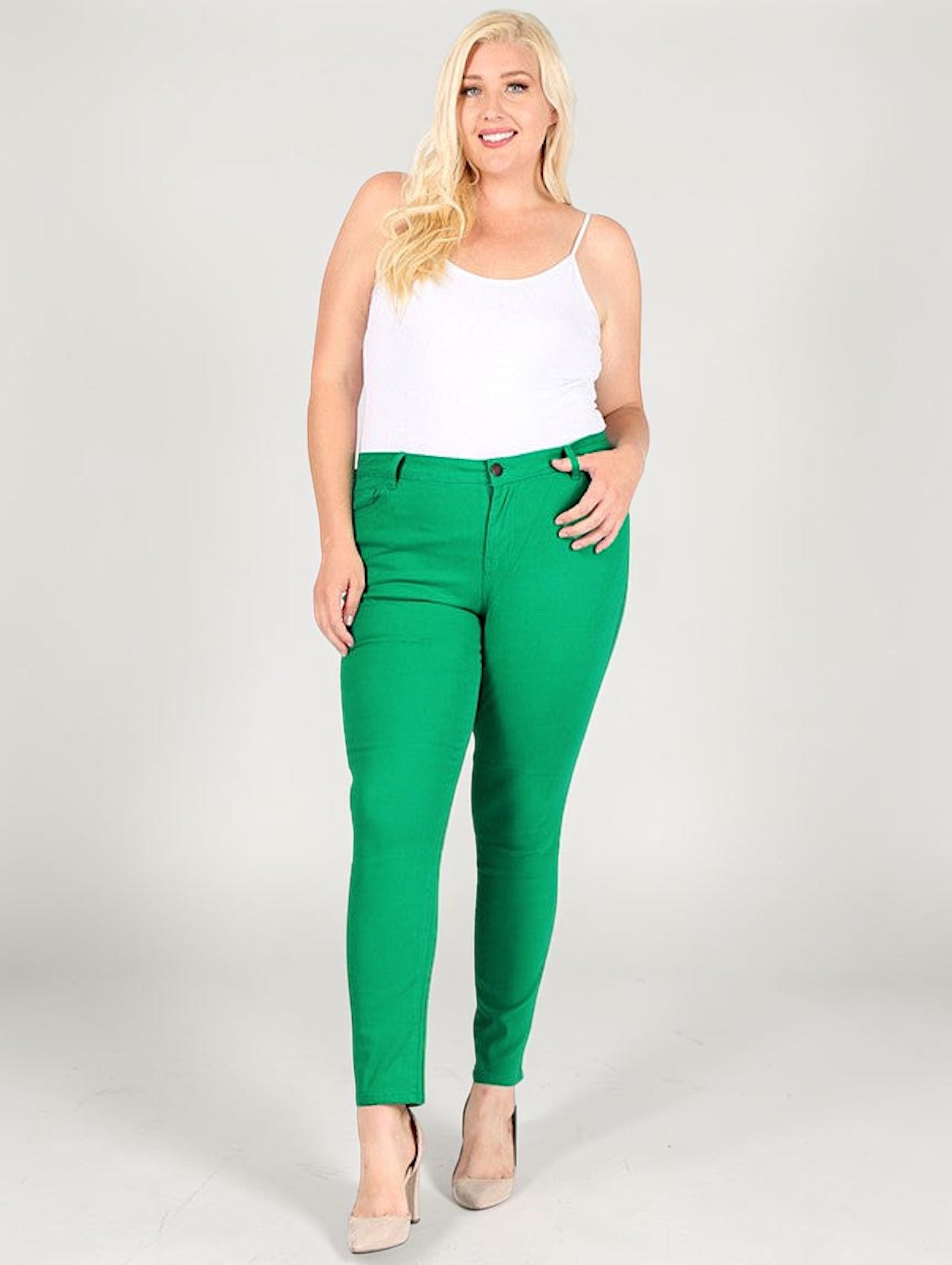 Woman wearing green pants and a white top on a plain background
