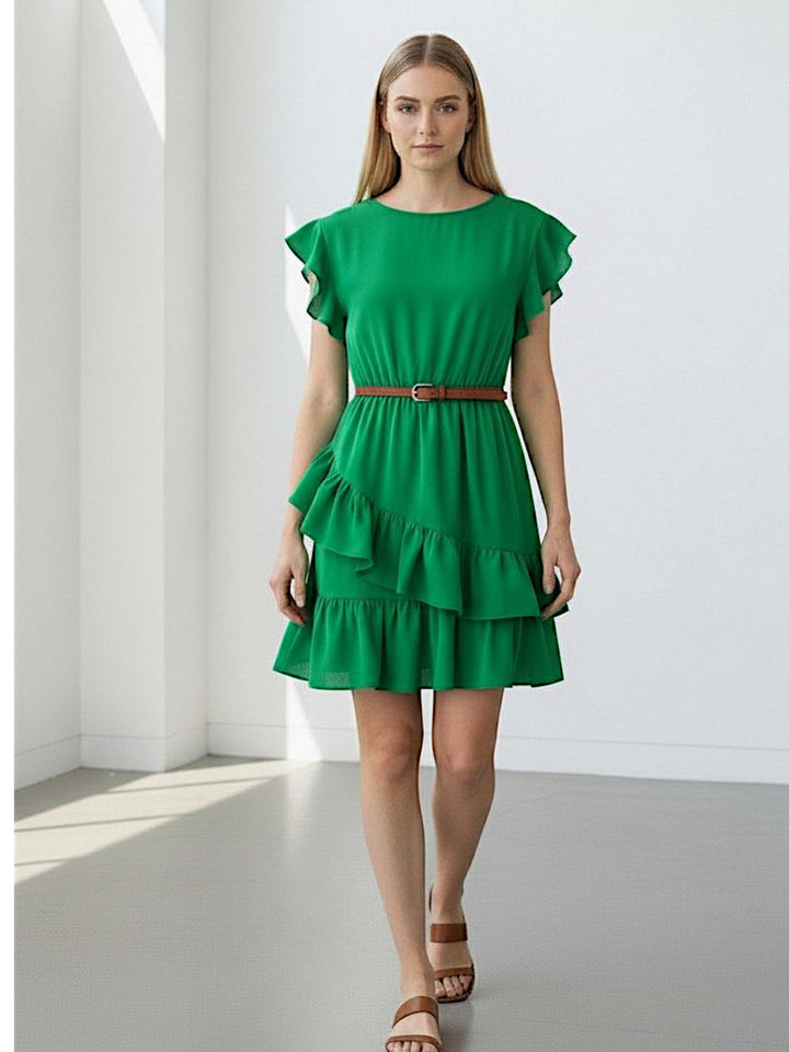 Woman wearing a green dress with ruffled layers in a minimalistic setting