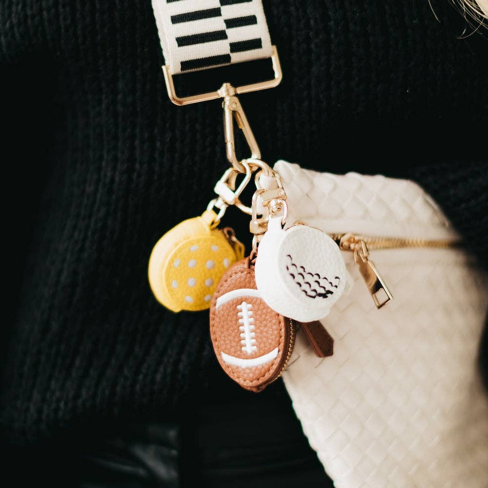 Keychain with various charms including a football, shoe, and heart on a dark background