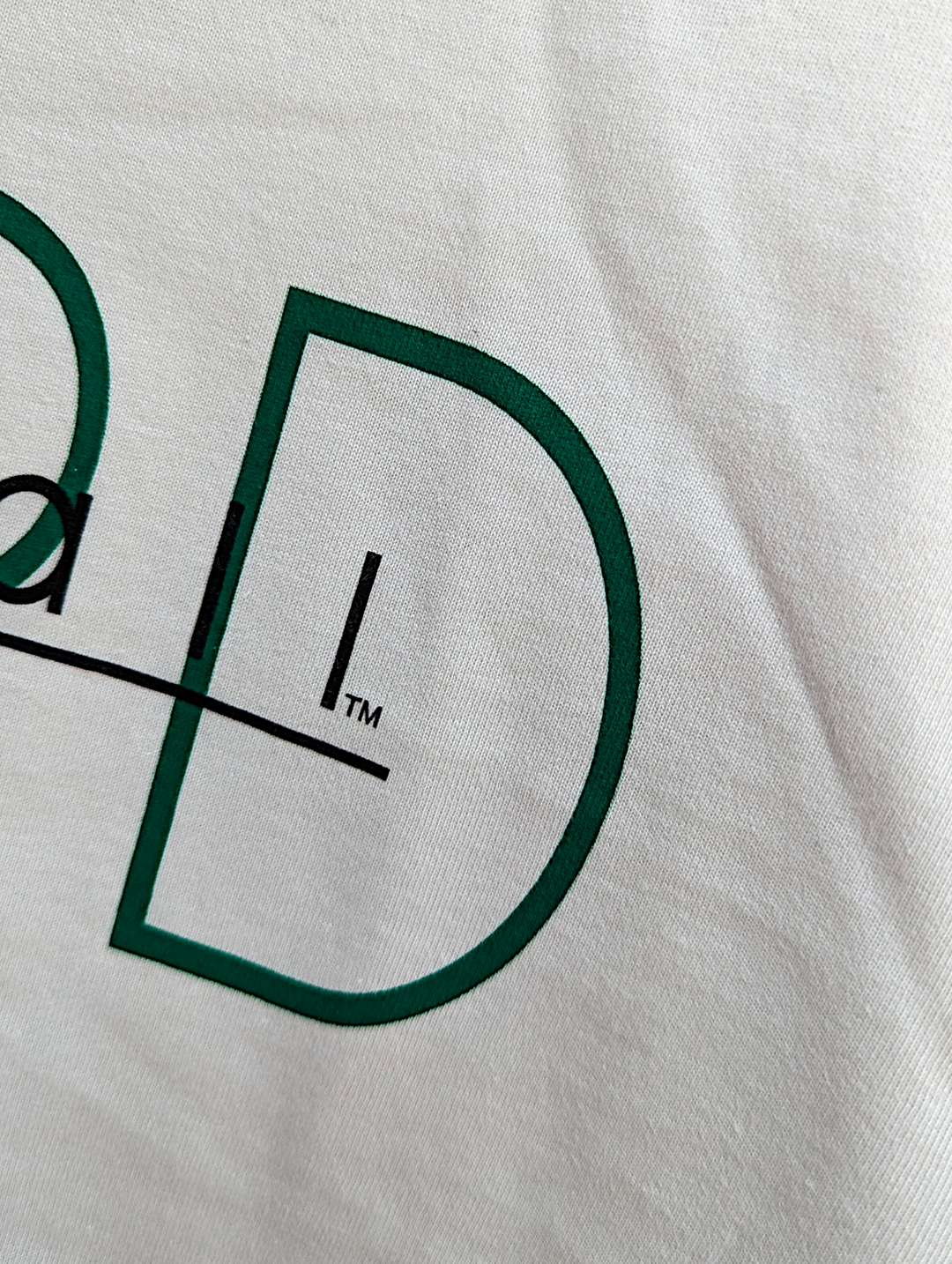 Close-up of a logo on a white shirt with green and black design.