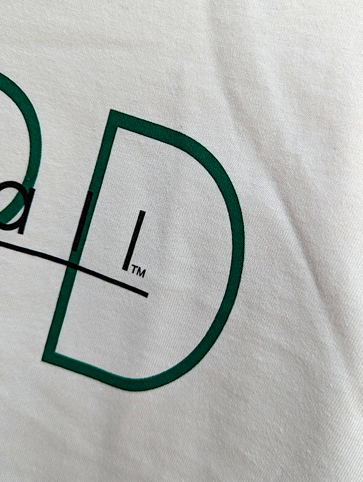 Close-up of a logo on a white shirt with green and black design.