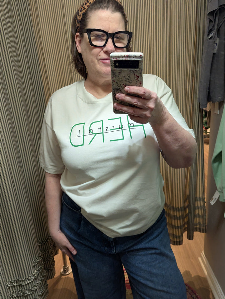 Person wearing a white t-shirt with green text in a clothing store.