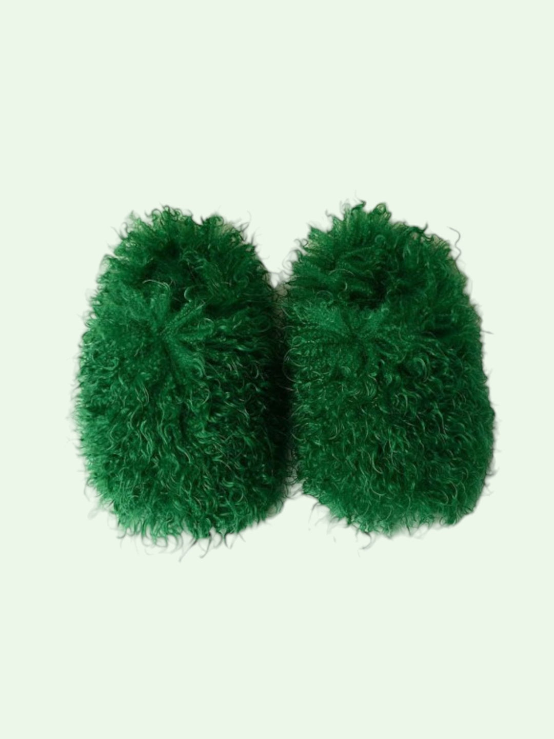 Pair of green fuzzy slippers on a light green background