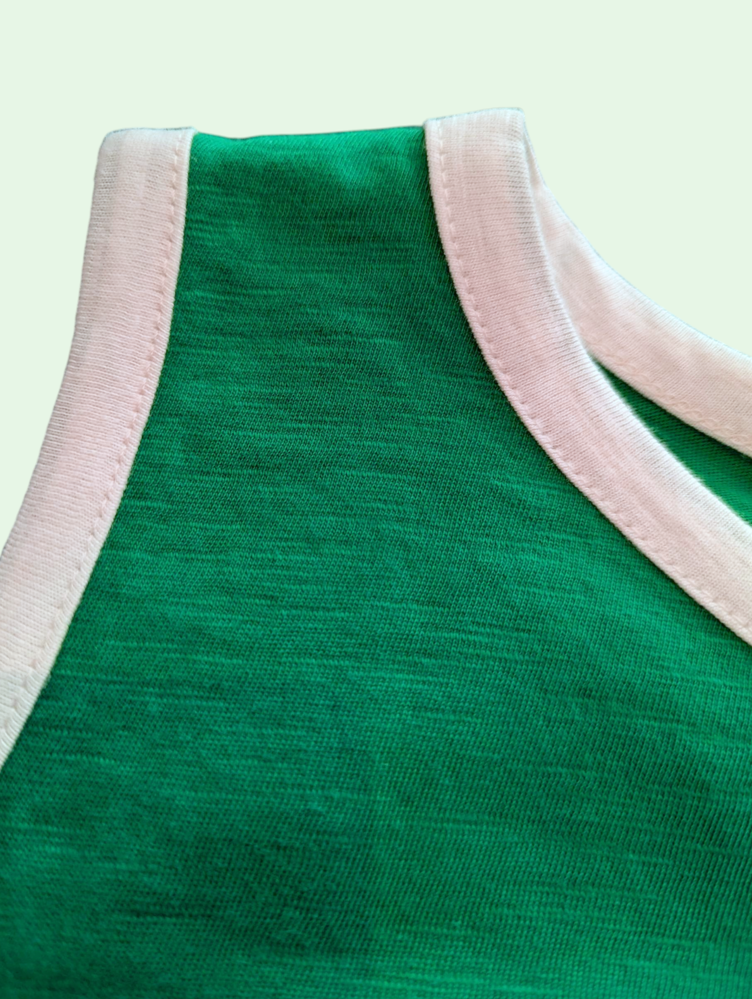 Green fabric with pink and white trim on a light green background
