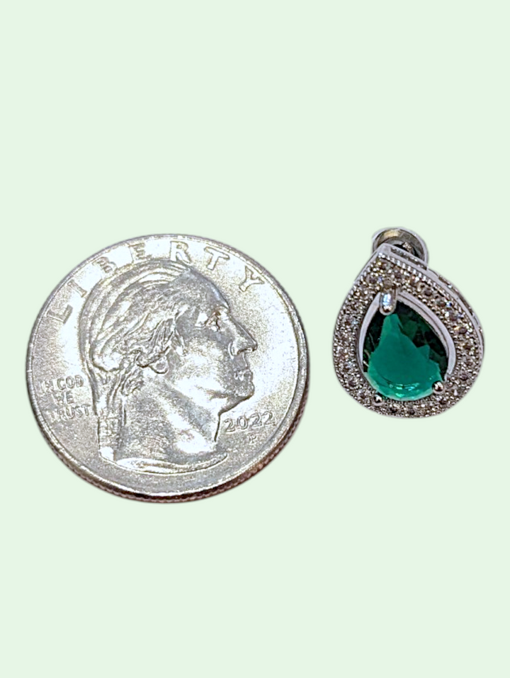 Teardrop-shaped green gemstone earring next to a quarter for size comparison on a white background