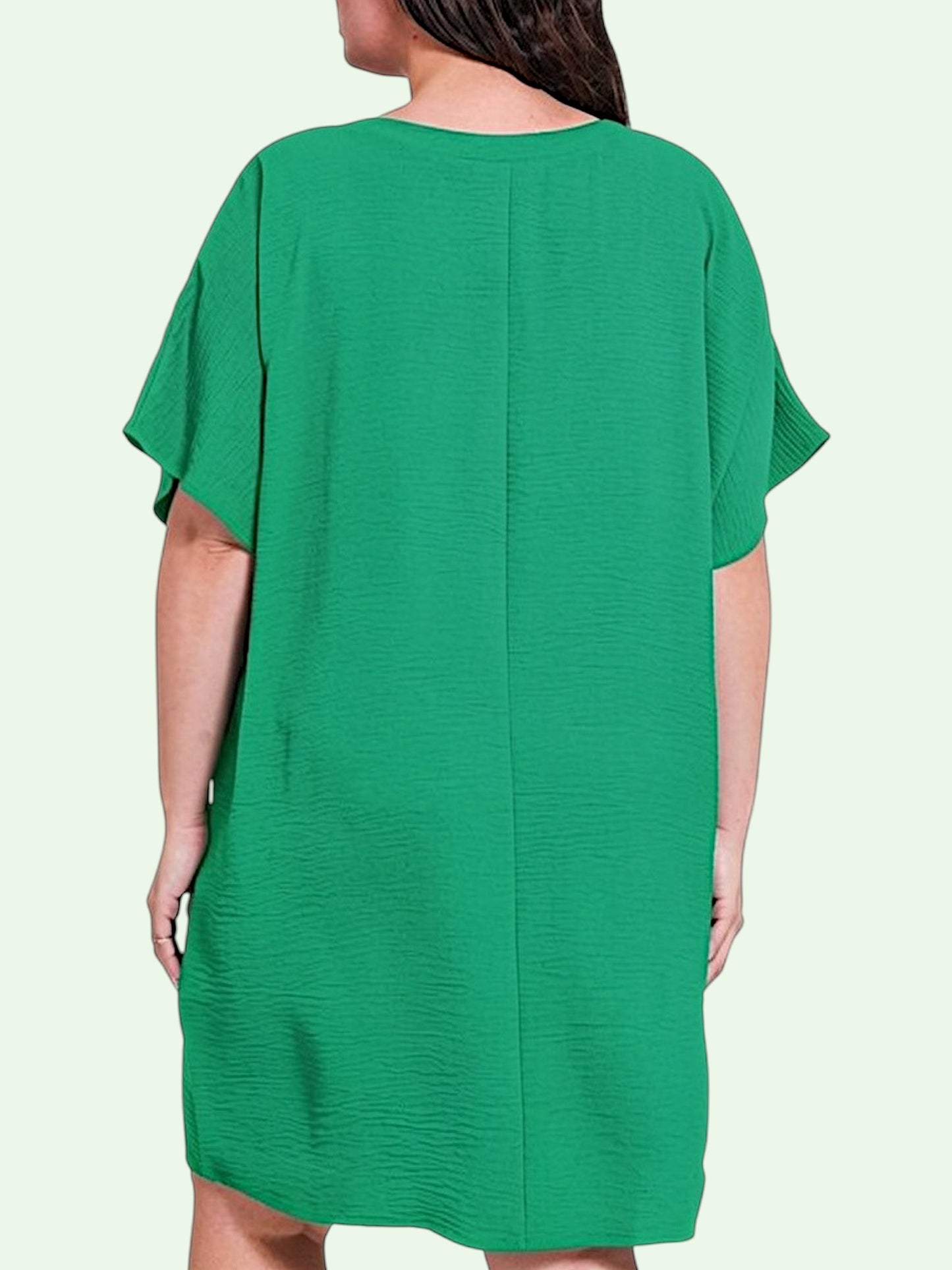 Green dress worn by a person on a light green background