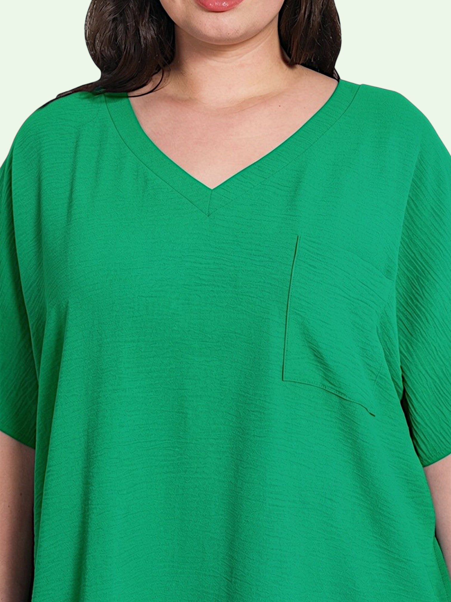 Green V-neck t-shirt with a pocket on a light green background