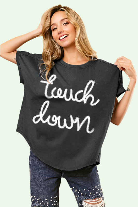 Woman wearing a black t-shirt with 'Touch Down' text in a decorative interior setting