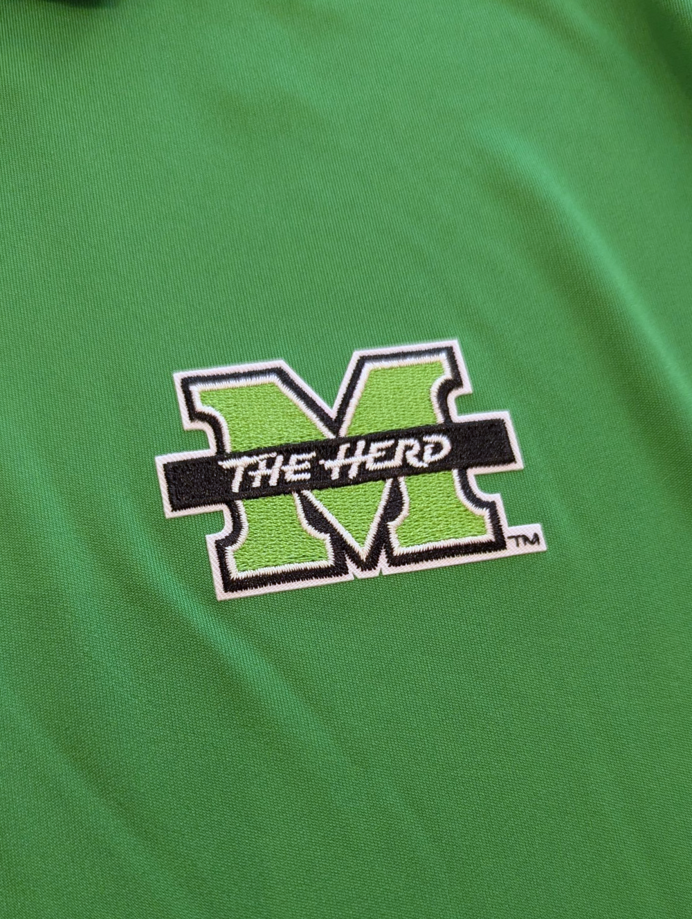 Green shirt with 'The Herd' logo on a green background