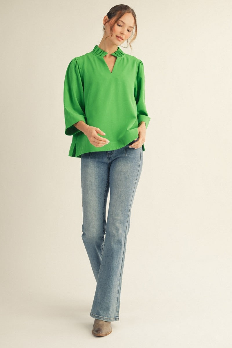Person wearing a green top and blue jeans on a beige background