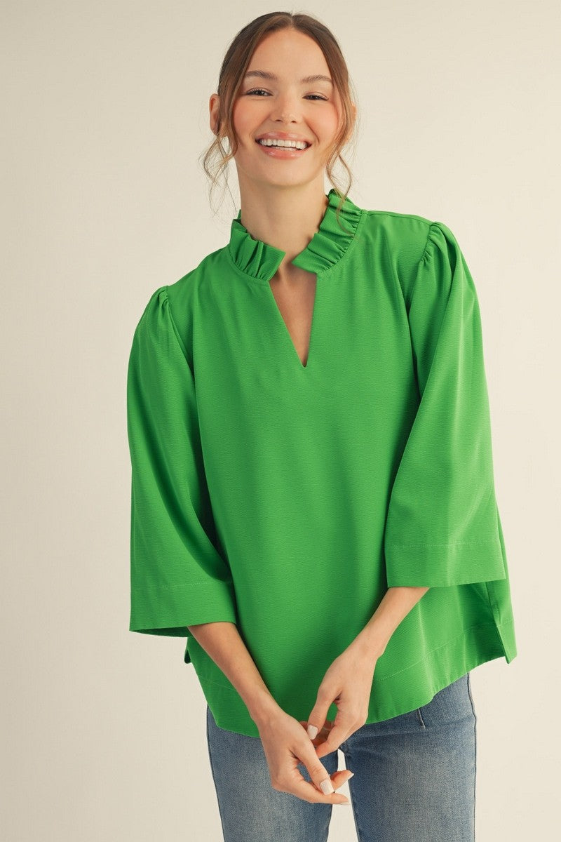 Woman wearing a green blouse with ruffled collar on a beige background