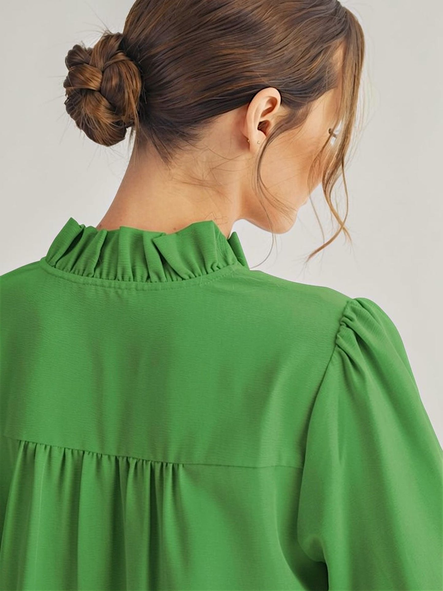 Green blouse worn by a person with a neutral background