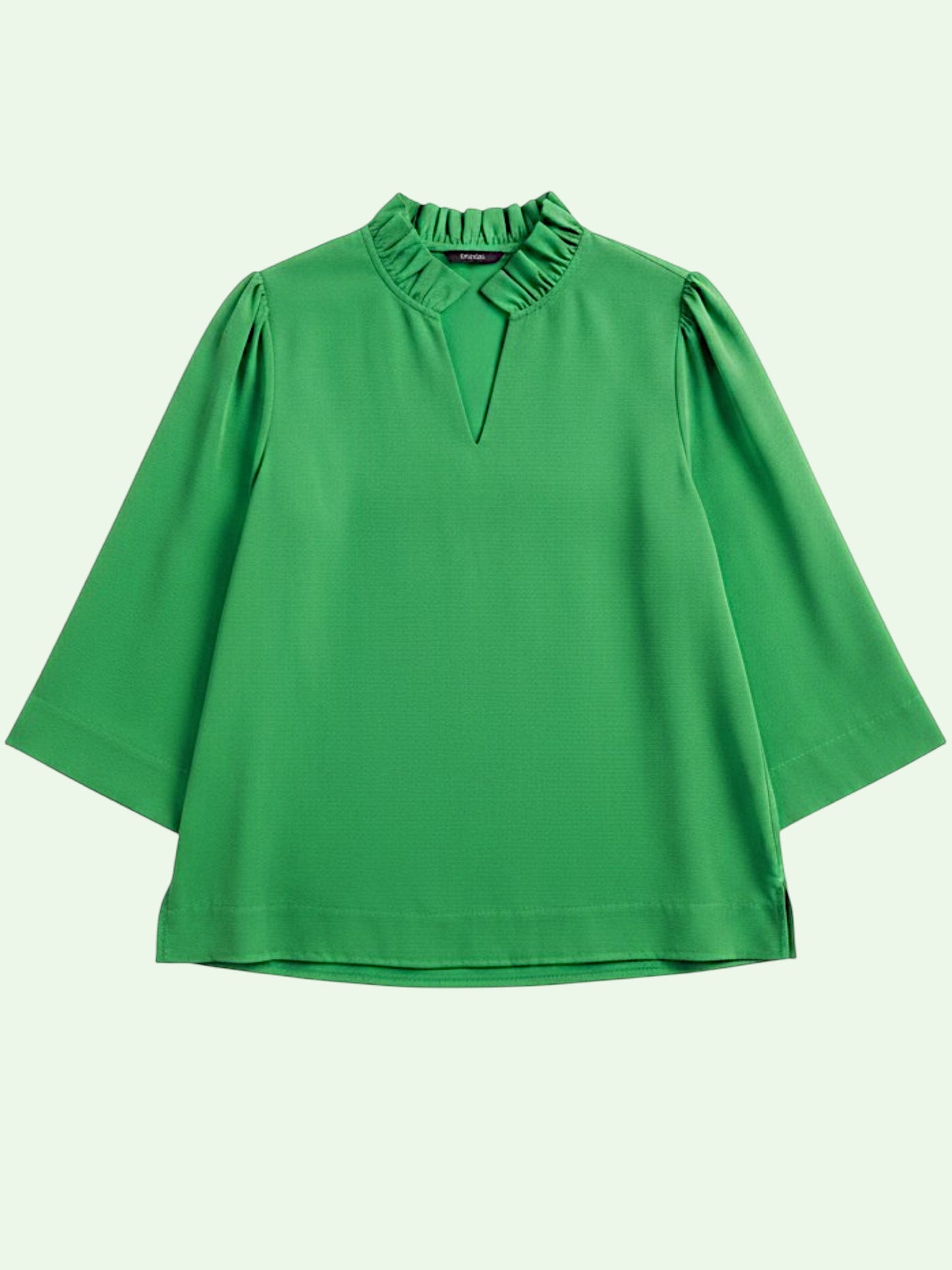 Green blouse with ruffled neckline on a light beige background