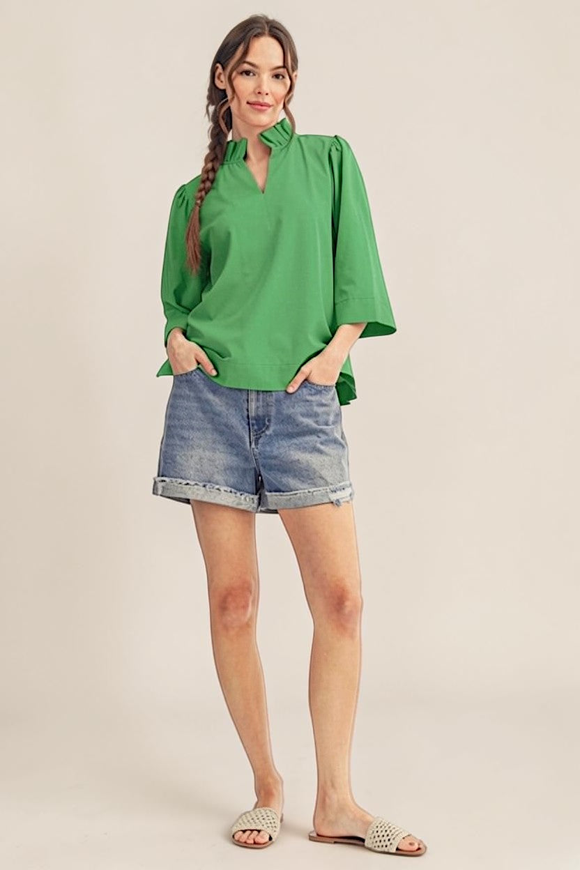 Woman wearing a green blouse and denim shorts on a beige background