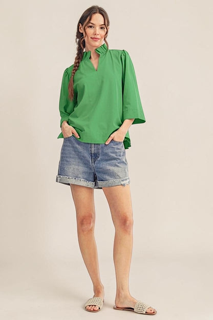 Woman wearing a green blouse and denim shorts on a beige background