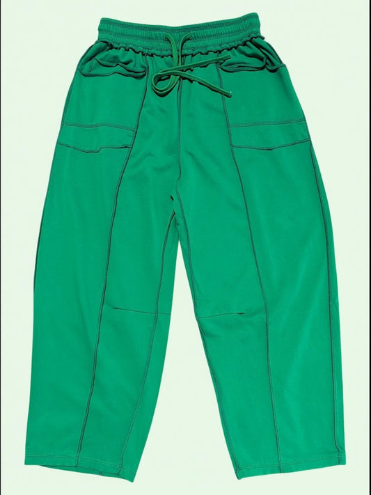 Green drawstring pants with side pockets, laid flat against a light off-white background.