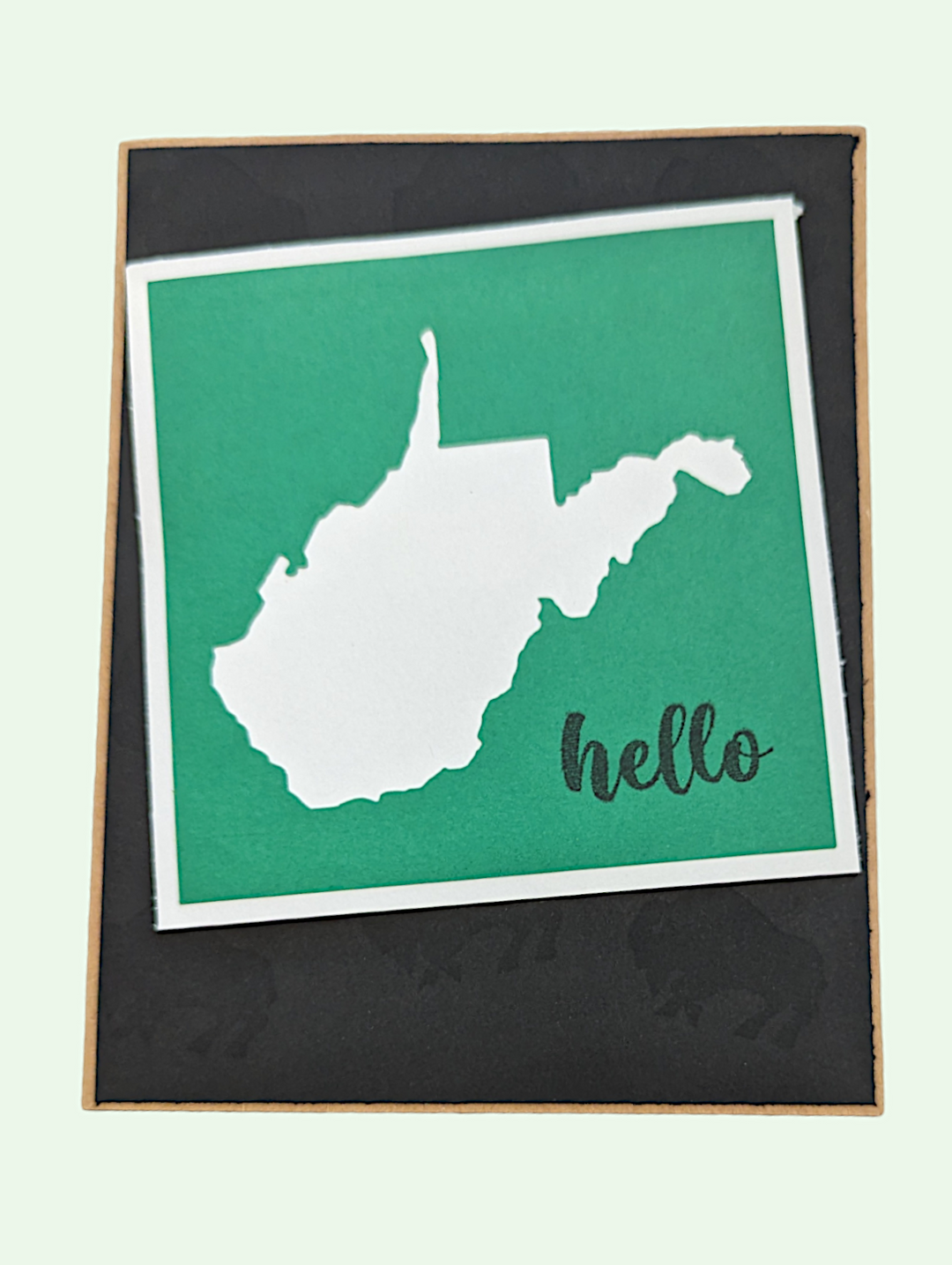 a greeting card with a white outline of wv on a green background on a black background