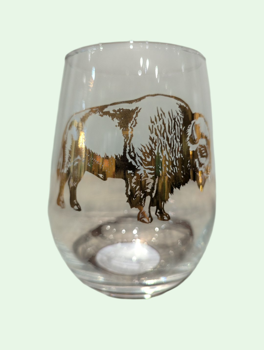 Clear glass with a gold bison design on a light green background