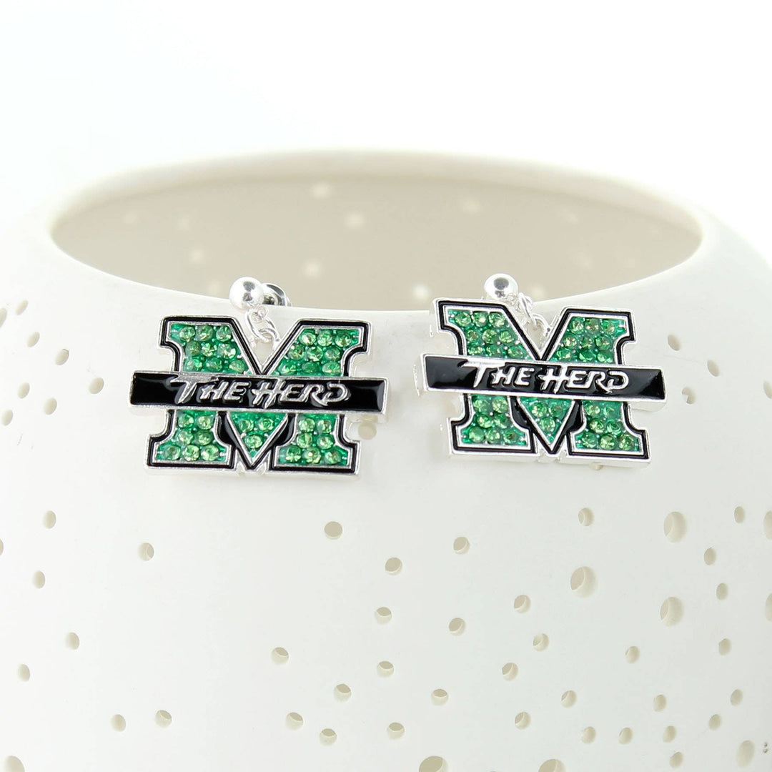 Silver plated post earrings with green rhinestone and black enamel Marshall logo charms. Hanging on the edge of a white bowl