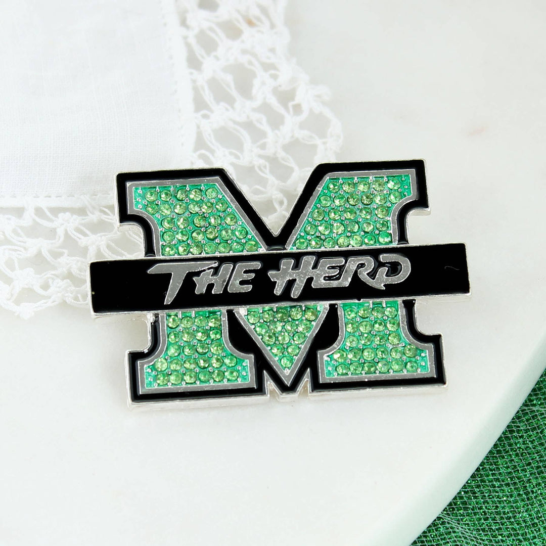 Silver tone Marshall logo pin featuring green rhinestones and black enamel. Pin measures approximately 2.25 in width”. On white background